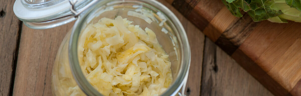 sauerkraut in jar and cutting board on wood table