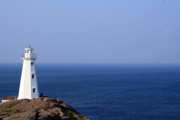 white lighthouse on a cliff by water